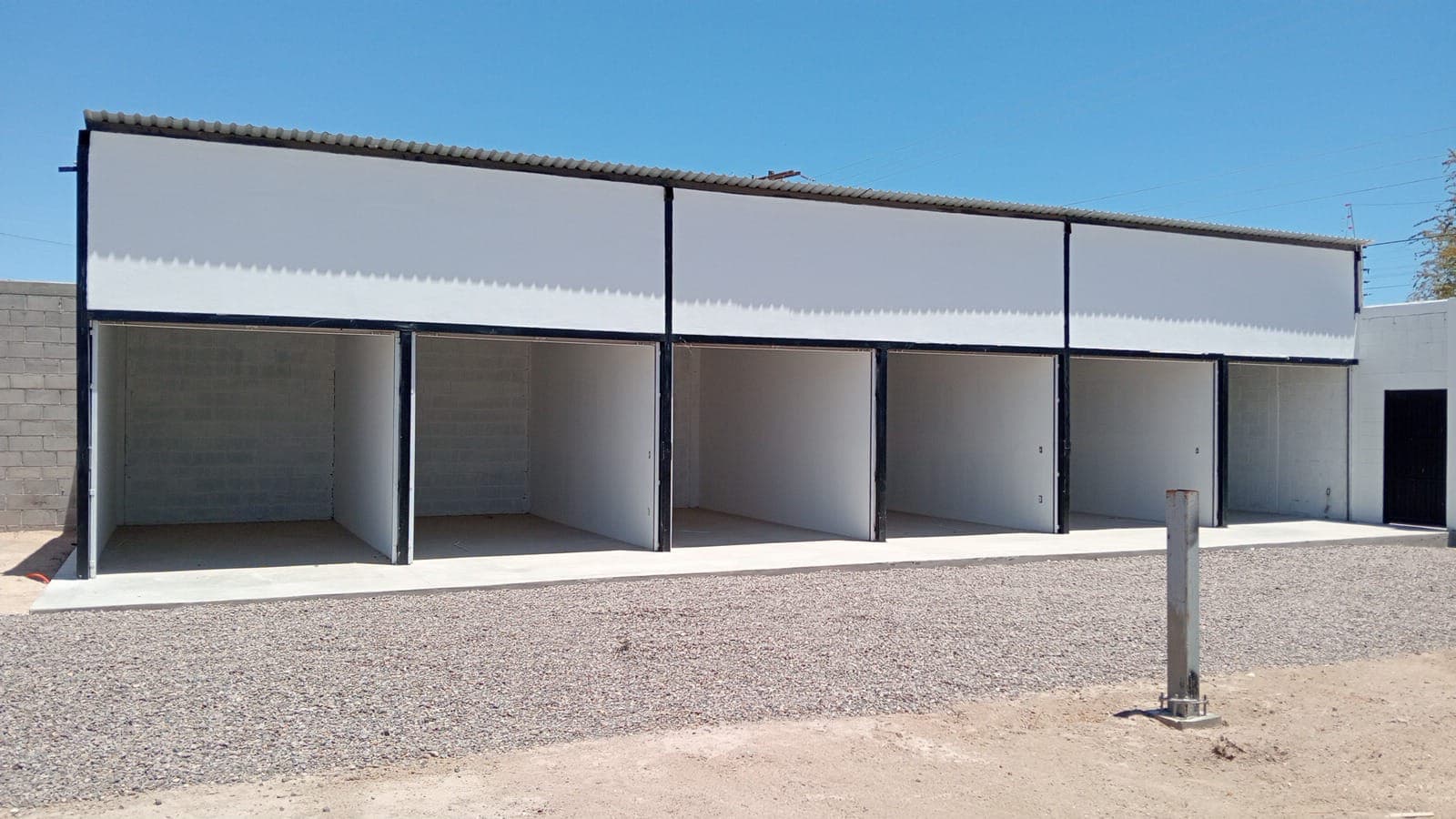 Hilera de seis bodegas nuevas con cortina metálica abierta en El Centenario, La Paz BCS